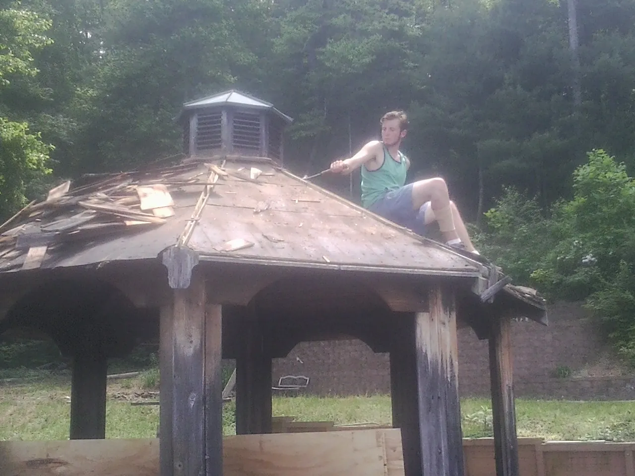 Tearing the old roof off a wooden gazebo before new shakes in Newark