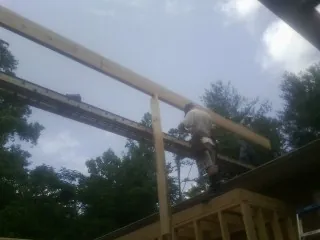 Carpenter setting a ridge beam over a new addition frame — Ice Dam Removal by Roofing Brothers in Newark